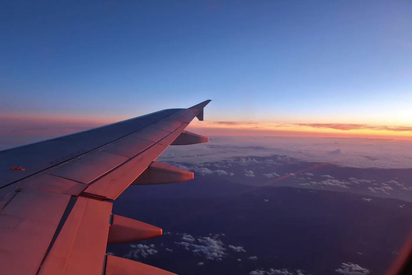 Vista da janela do avião com a asa sobre as nuvens ao entardecer